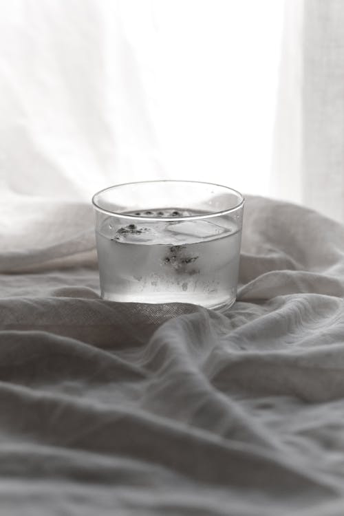 Close-Up Shot of Water with Ice Cubes on White Textile