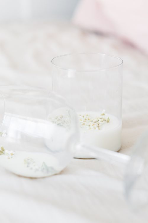 Free A minimalist close-up of milk in clear glasses with delicate flowers on a soft surface. Stock Photo