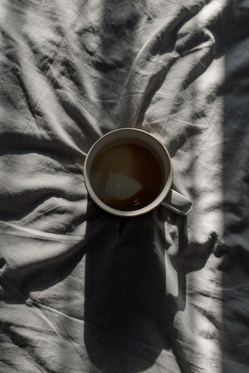 Free Top view of a coffee cup casting dramatic shadows on fabric in soft light. Stock Photo