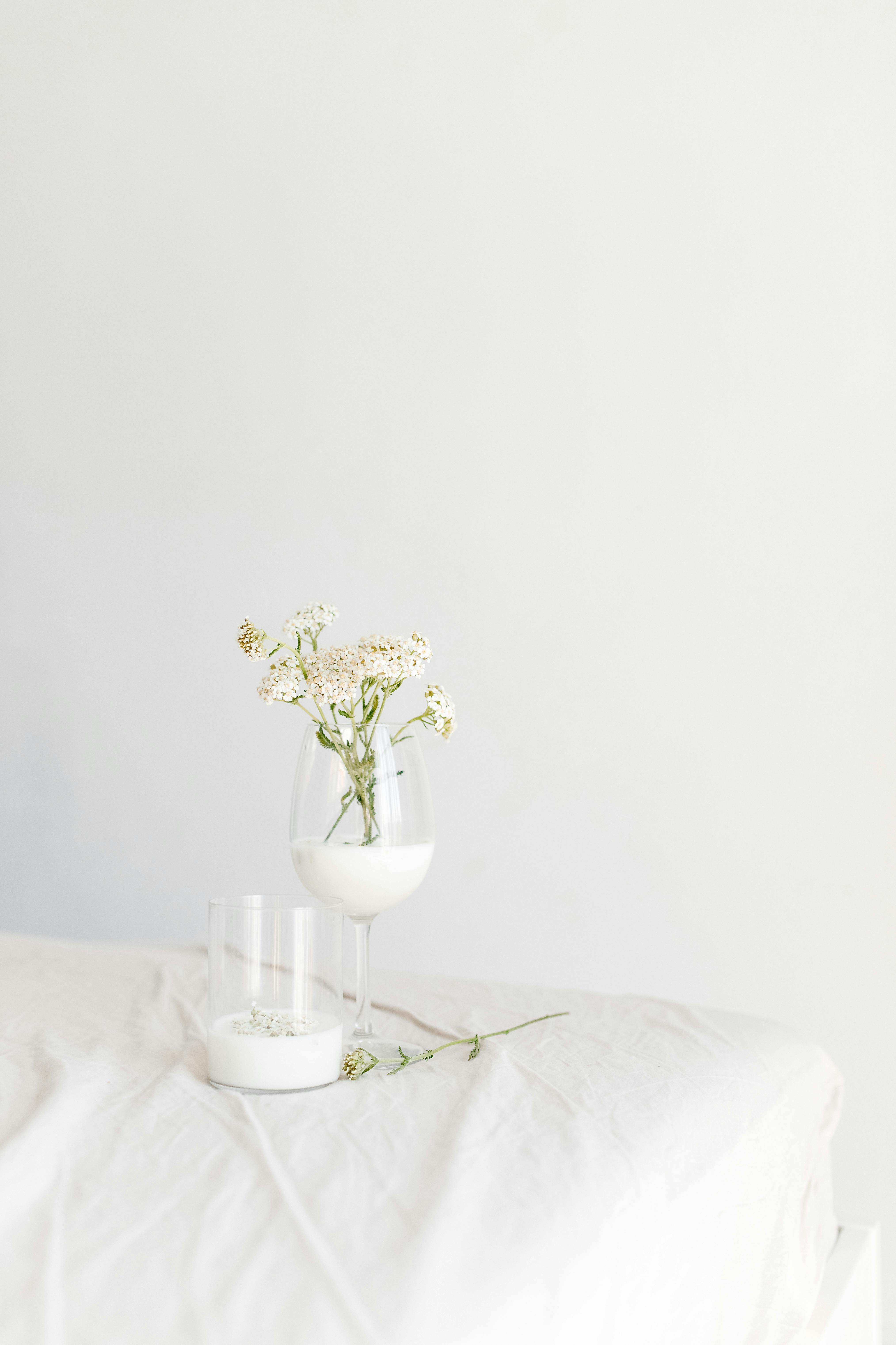 white flowers in clear glass vase on white table cloth