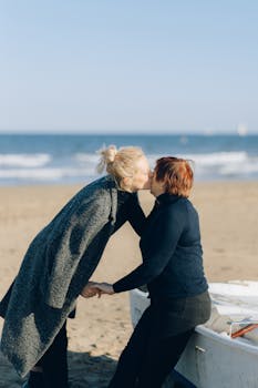 Two adults share a romantic moment on a sunny beach, capturing love and togetherness.