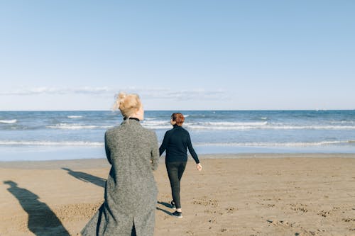 Woman in Black Long Sleeve Dress Standing on Beach
