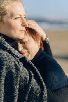 A heartwarming portrait of a mother and daughter embracing on a sunny beach.