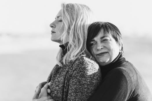 A touching black and white portrait of a mother hugging her daughter on the beach.