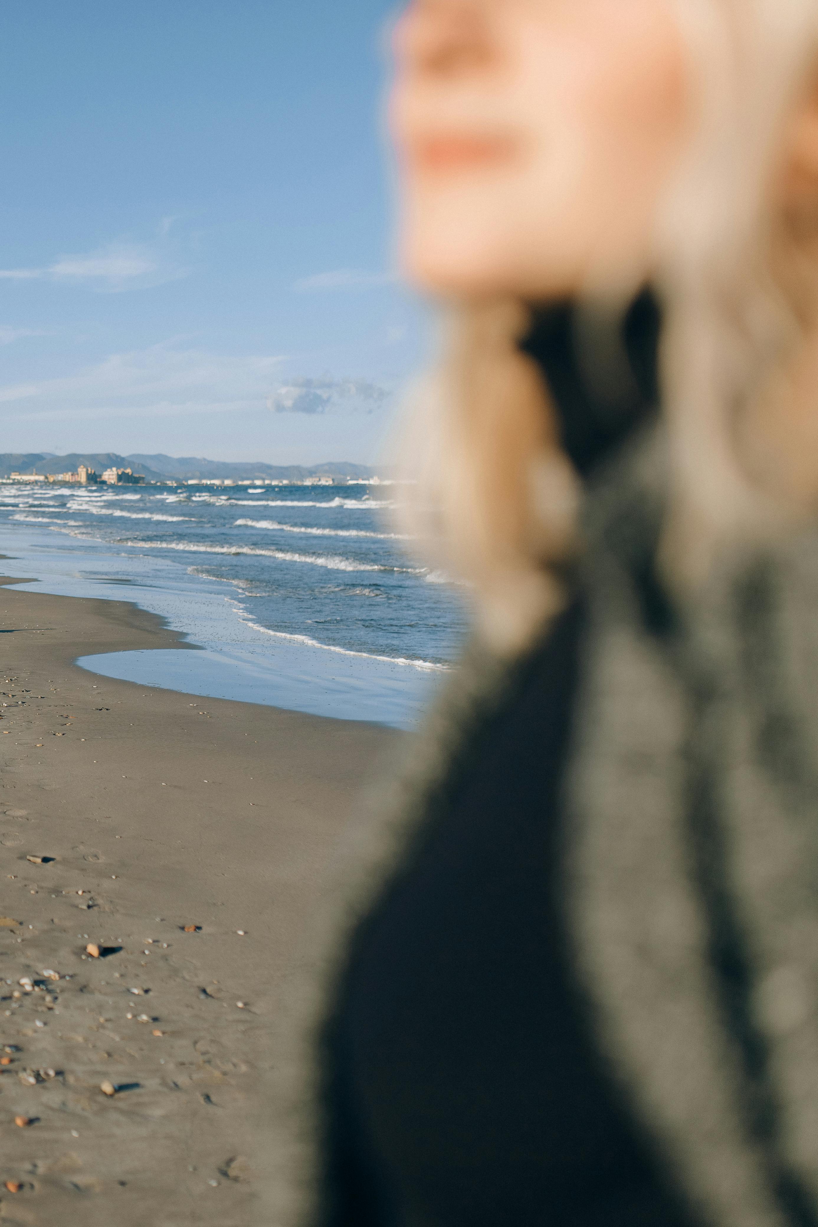一个人模糊的焦点与阳光明媚的海滩和波浪的背景，捕捉一个宁静的时刻
