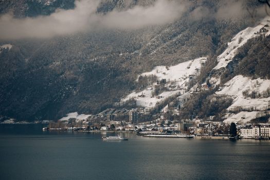 从空中俯瞰冬季的湖镇，白雪皑皑的山脉环绕，景色宁静如画