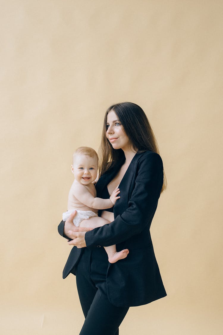 A Woman In Black Blazer Carrying Her Baby