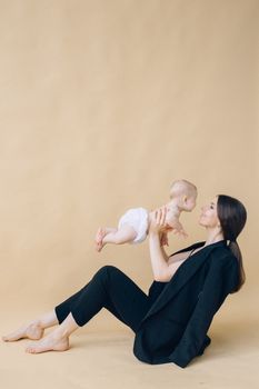 身着黑色西装的女人在室内欢快地举起婴儿，捕捉家庭欢乐