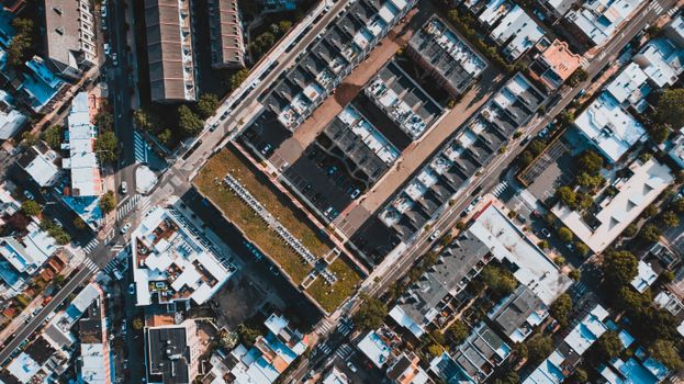Aerial view of vehicles driving on asphalt roadway between buildings and trees in city