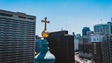 从无人机视角看去，教堂的圆顶闪闪发光，金色的十字架矗立在城镇的现代石质建筑之间