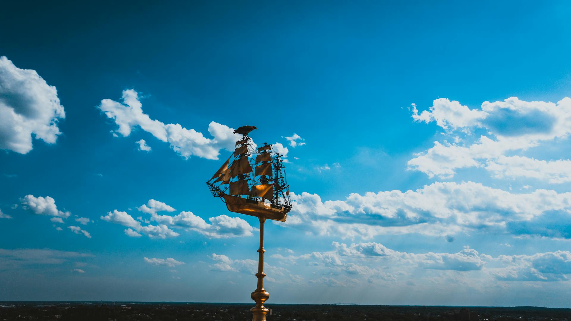 Ornate golden ship sculpture set against a vibrant blue sky, Philadelphia.