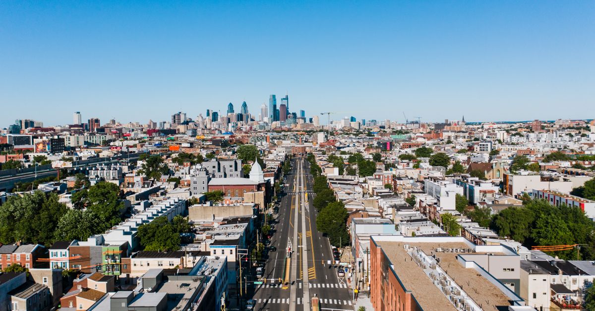 Aerial view of straight roadway between contemporary dwelling house facades in city in daylight