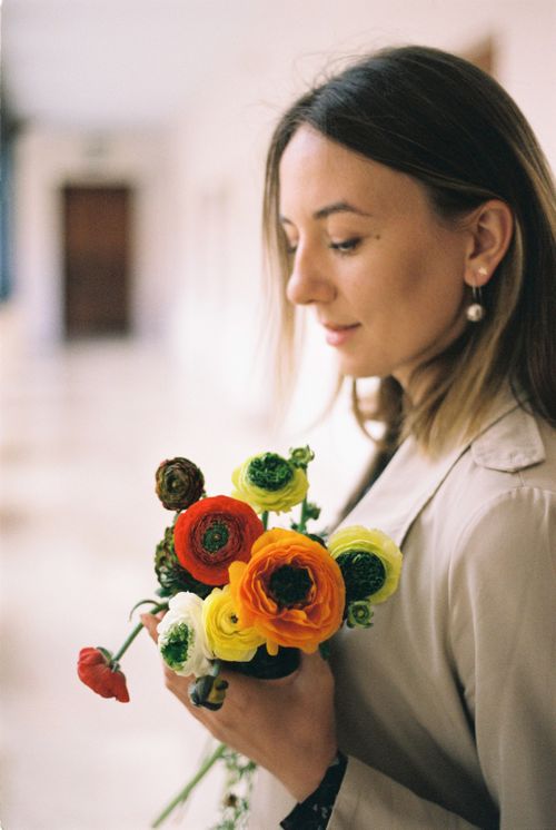 Free A peaceful woman holding vibrant ranunculus flowers indoors. Stock Photo