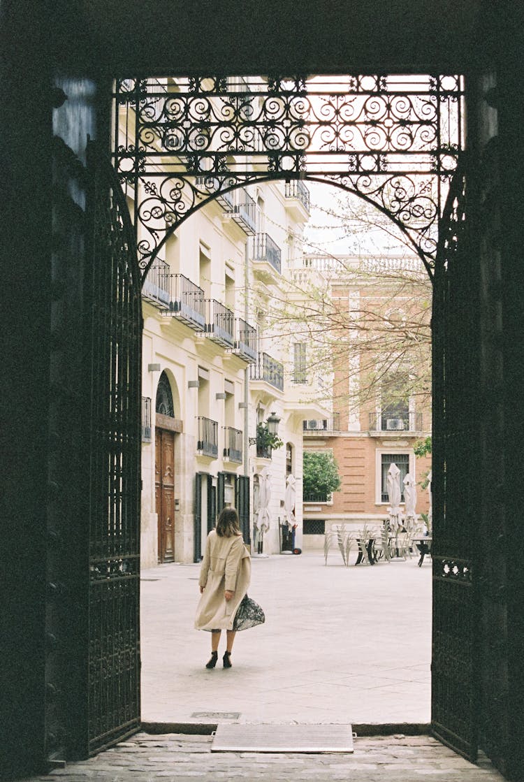 Back View Of A Woman In Trench Coat Standing Near A Building