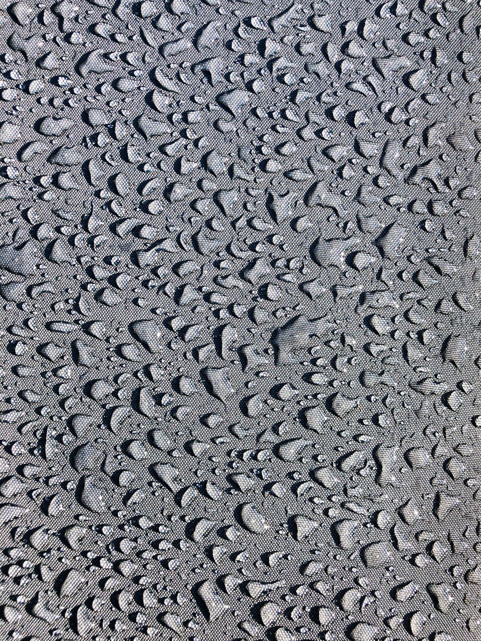 Gouttes perlant sur une paroi Gouttes d’eau perlant sur une surface texturée sombre, phénomène de condensation