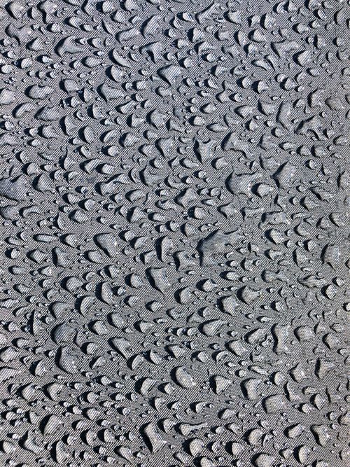 Free Close-up of raindrops on a textured surface creating artistic patterns. Ideal for backgrounds. Stock Photo