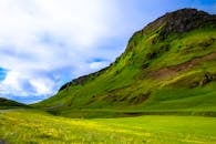 这里有一片充满活力的景观，绿色的山脉与蓝天相映，云朵点缀其间，非常适合自然爱好者