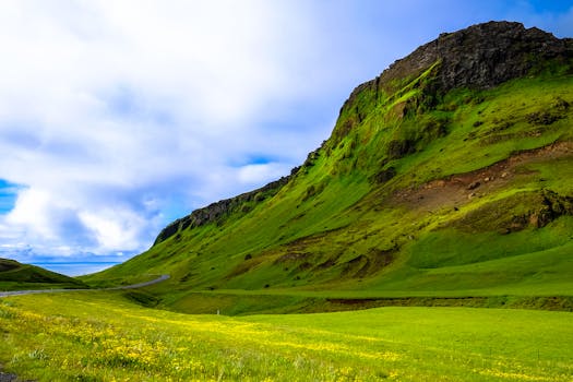 这里有一片充满活力的景观，绿色的山脉与蓝天相映，云朵点缀其间，非常适合自然爱好者