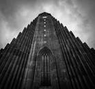 在多云的天空下，从低角度拍摄的哥特式大教堂塔楼显得格外戏剧性