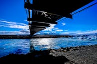 在冰冷的蓝色水域上，一座桥横跨而过，背景是生动的天空，构成了一幅令人惊叹的景观