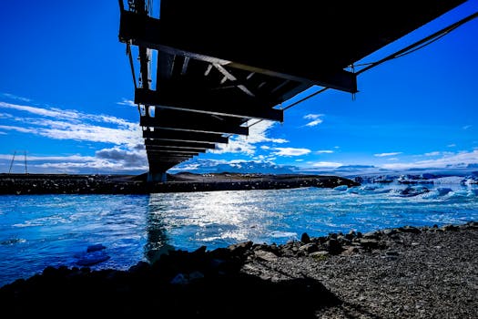 在冰冷的蓝色水域上，一座桥横跨而过，背景是生动的天空，构成了一幅令人惊叹的景观