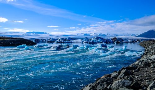 Free Explore this stunning glacier landscape featuring icebergs, bright skies, and a serene river flowing through icy terrain. Stock Photo