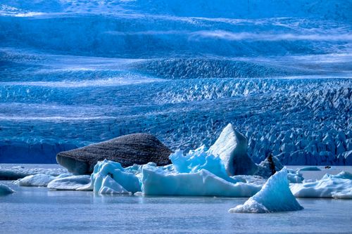 Free A serene landscape of icebergs and glacial formations reflecting on calm waters in an Arctic setting. Stock Photo