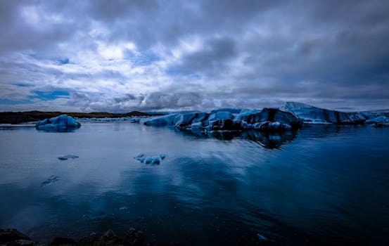 Serene icy landscape with floating icebergs and dramatic sky reflections.