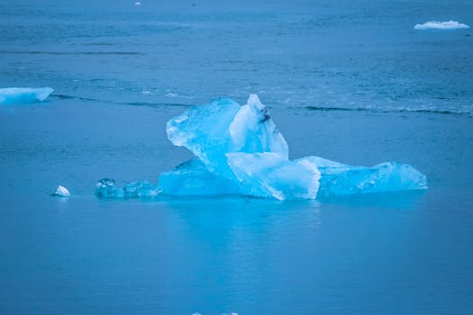 在宁静的海洋中，一座醒目的蓝色冰山漂浮着，展示了大自然的美丽