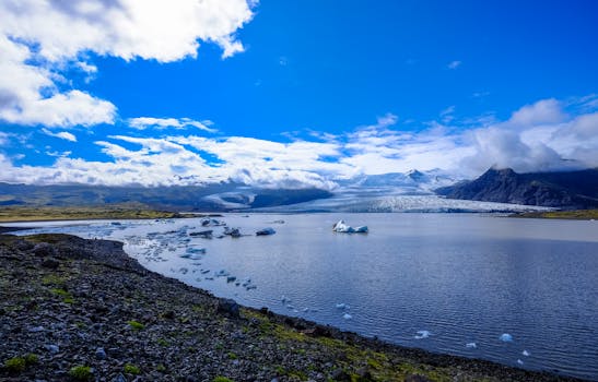 Breathtaking view of a glacier lagoon with floating icebergs and majestic mountains under a blue sky.