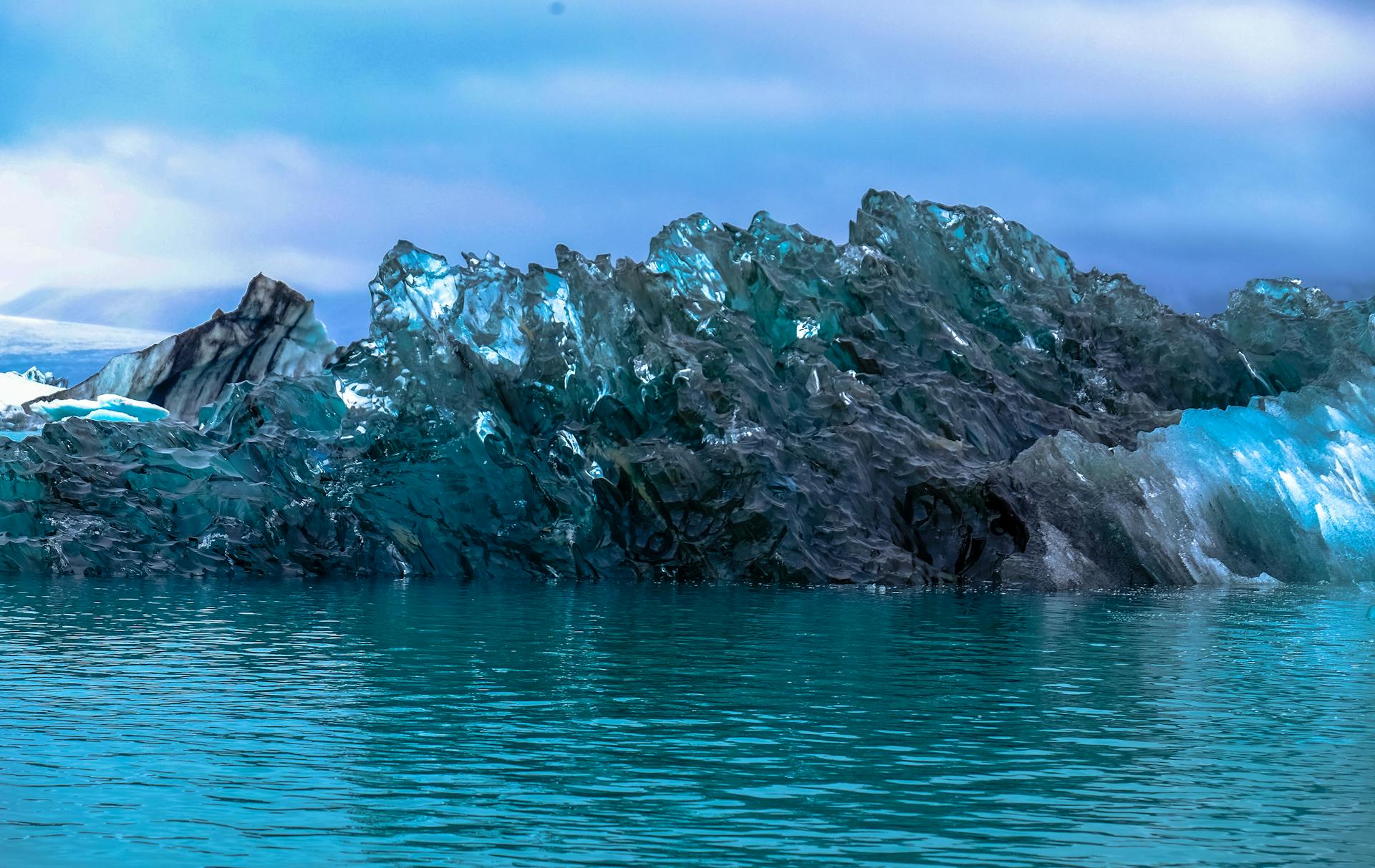 A stunning view of a turquoise iceberg floating in cold, serene Arctic waters.