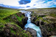 在偏远的自然环境中，迷人的瀑布流经岩石地形和充满活力的绿色苔藓