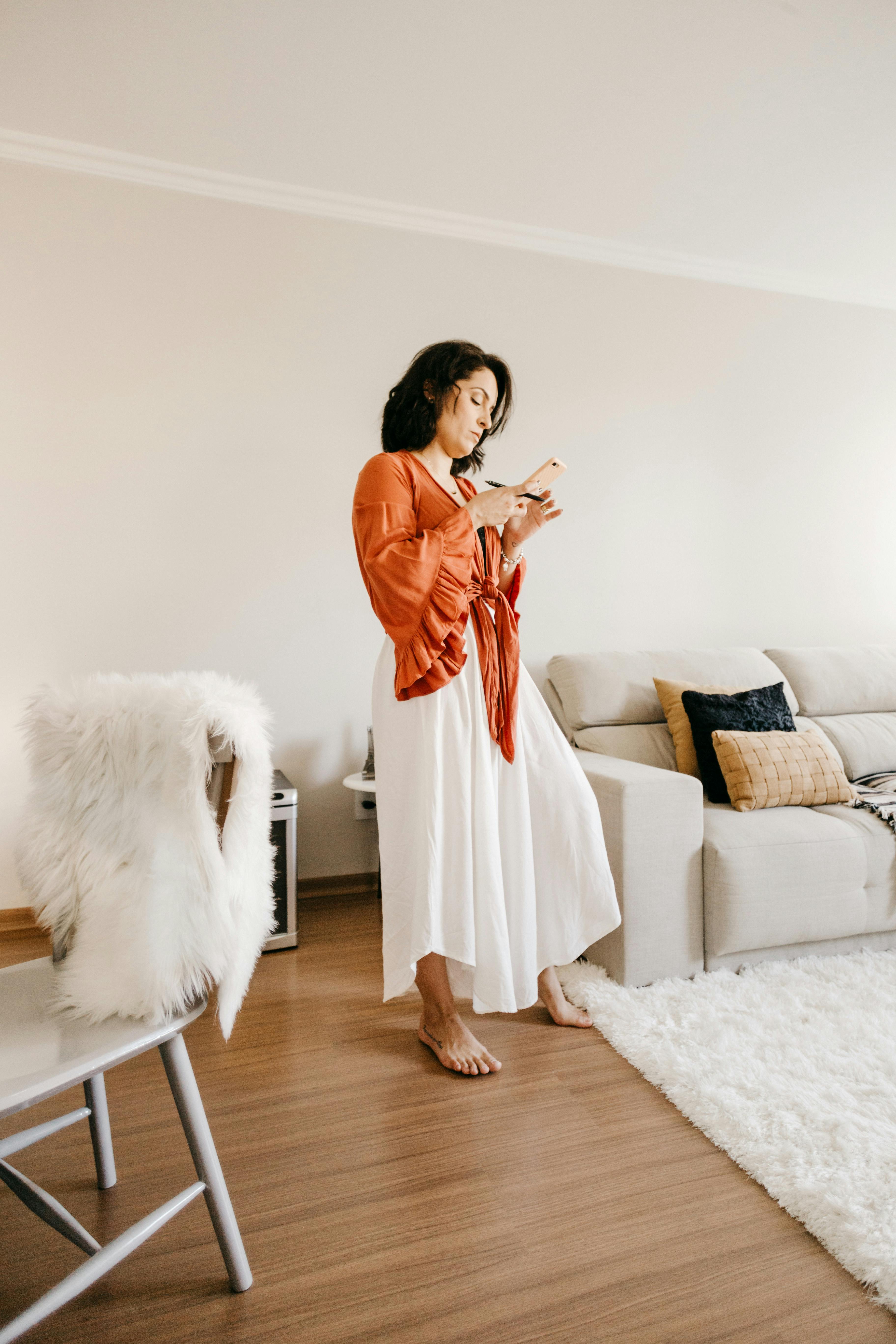 stylish woman surfing internet on smartphone in living room