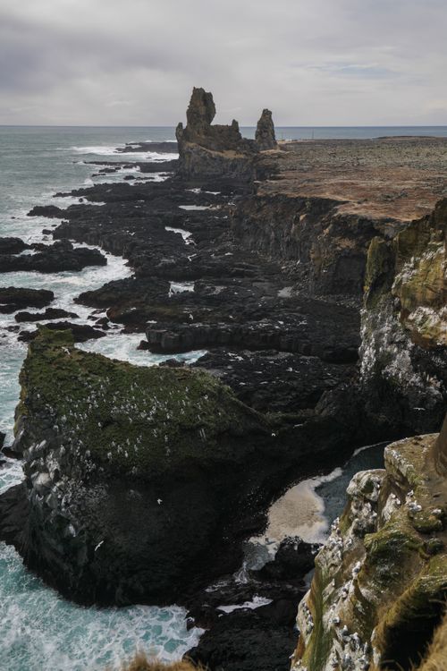 Free Majestic cliffs with rugged coastline and crashing ocean waves under a moody sky. Stock Photo