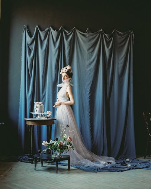 Woman in White Dress Standing Beside Table