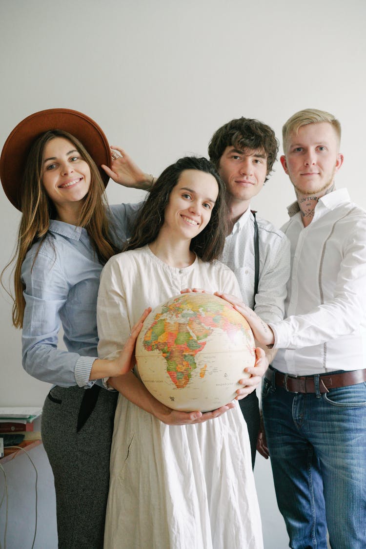 People Standing Close Together Touching A Desk Globe