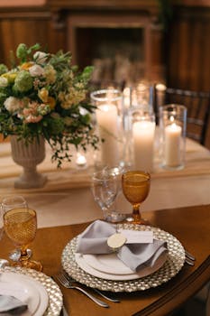 Sophisticated table setting with candles, flowers, and elegant glassware in a warm indoor atmosphere.