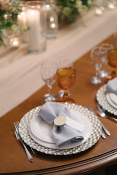 Elegant table setup featuring cutlery, glassware, and napkin on a decorative plate.