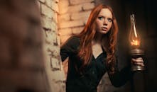 A Woman in Black Long Sleeve Shirt Holding a Kerosene Lamp