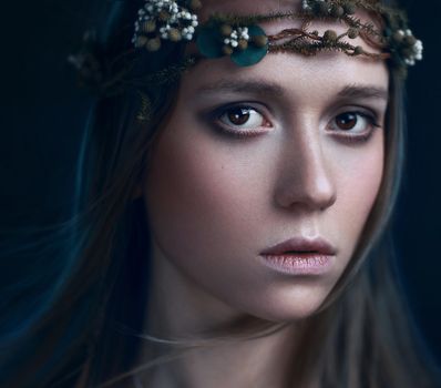 Close-up portrait of a woman wearing a delicate floral wreath, exuding elegance and beauty.