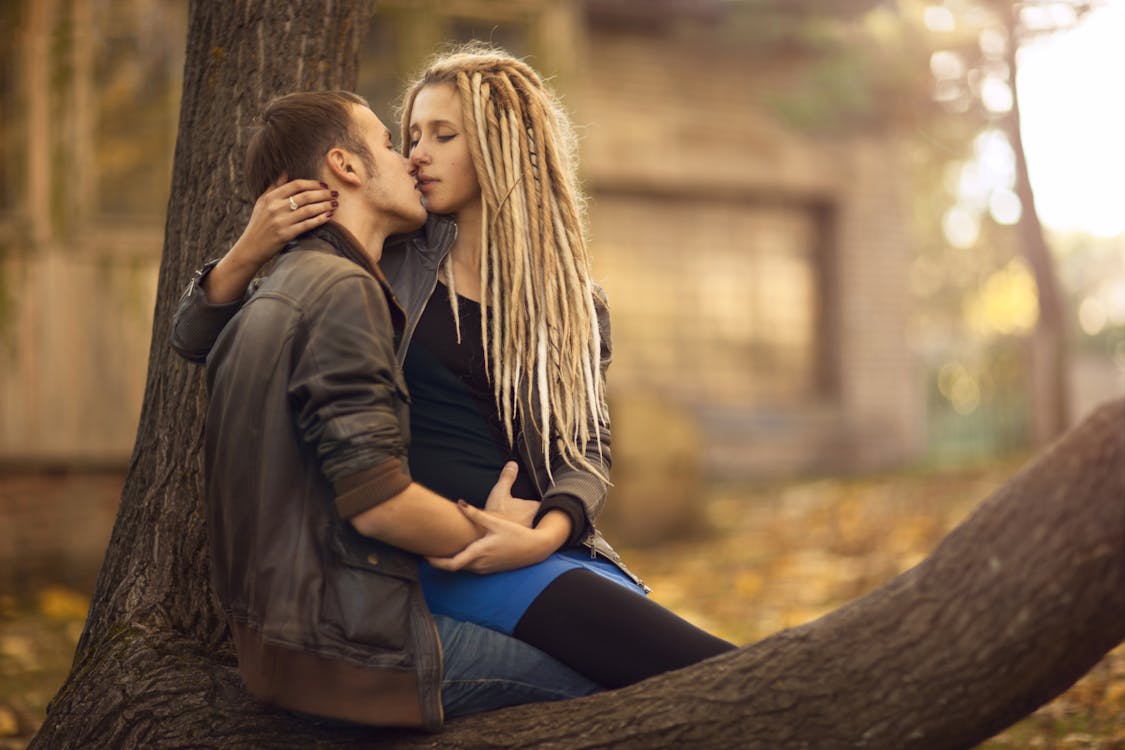 Free A Couple Sitting on a Tree Kissing Stock Photo