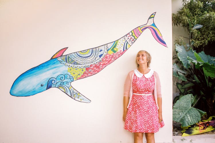 A Woman Standing Beside A Wall With Whale Painting