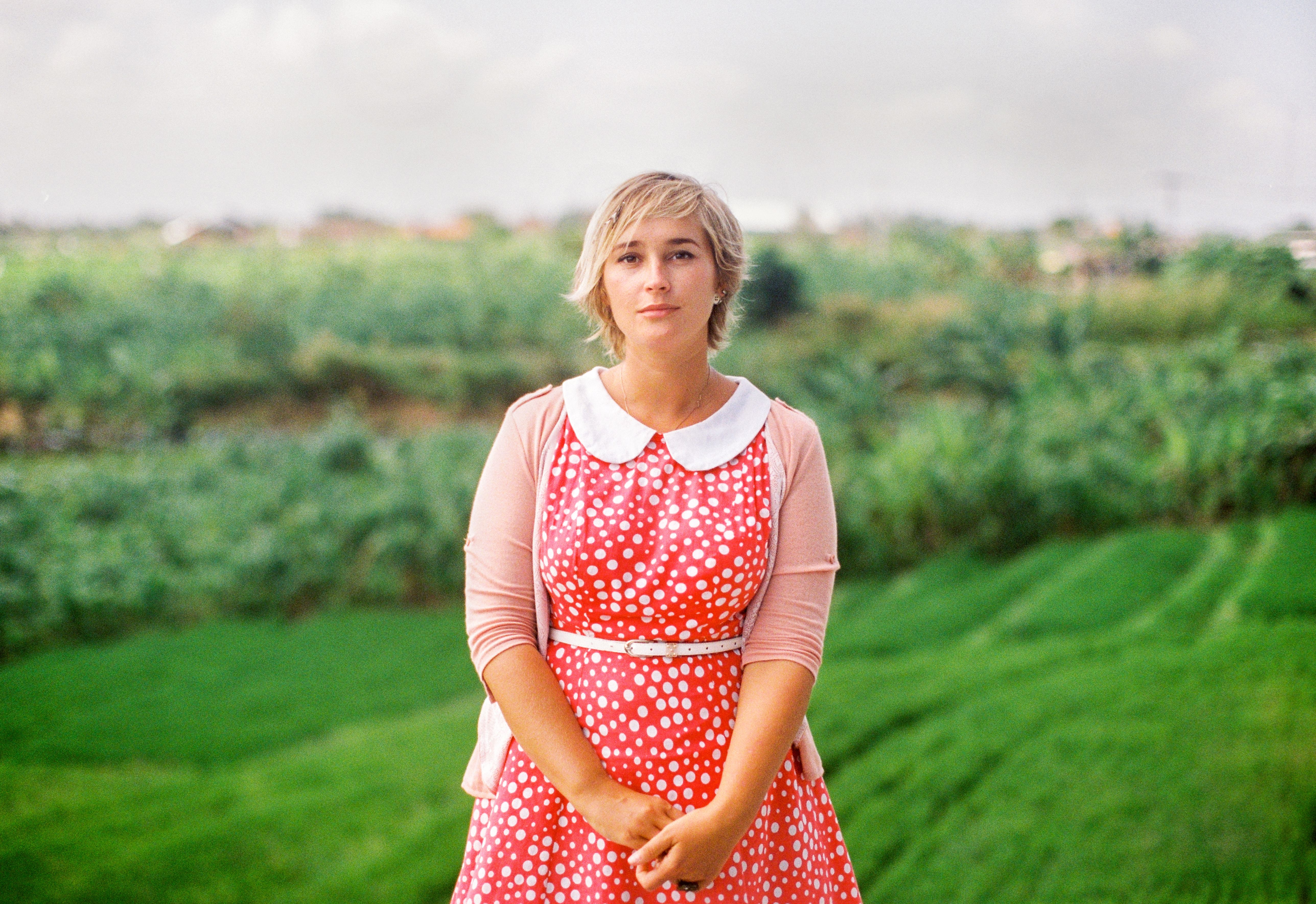 A Woman in Red and White Polka Dot Dress Standing on Green Grass Field ...