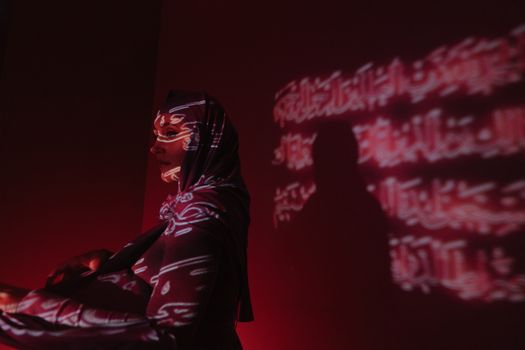 阿拉伯文字的艺术投影在一位女性的头巾上，散发着神秘与文化表达的气息