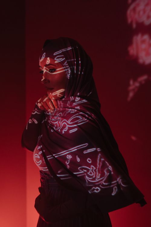 Free Red light projections create a surreal atmosphere around a woman in traditional attire, evoking mystery. Stock Photo