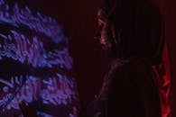 一个戴头巾的女人被阿拉伯书法投影照亮，投下富有表现力的红色阴影