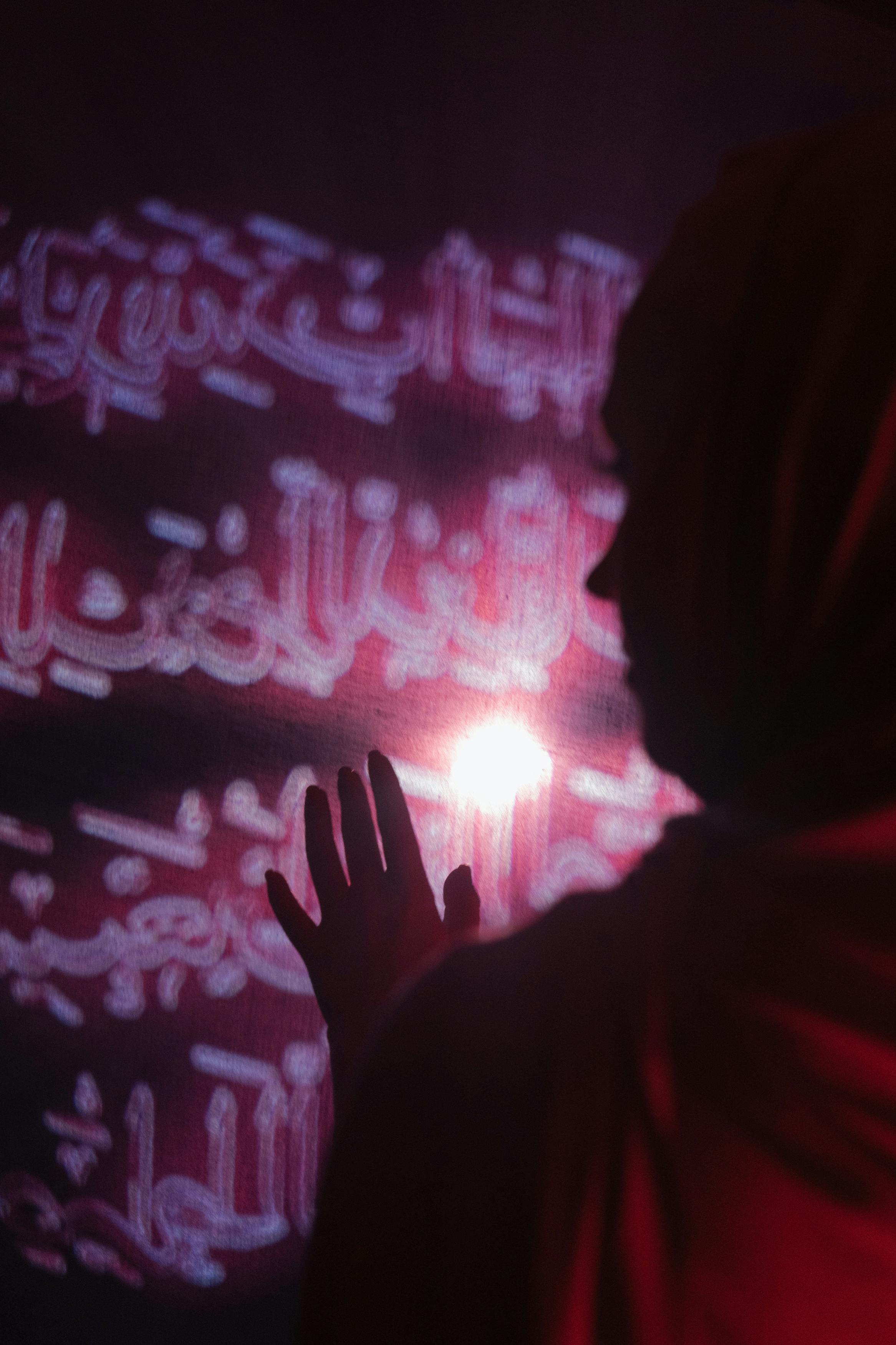 女人触摸着发光的阿拉伯书法投影的剪影