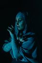 一个女人在室内神秘地摆姿势，头巾与艺术蓝色投影相映