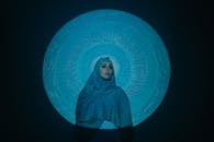 Woman in Blue Hijab Standing Beside Blue and White Wall