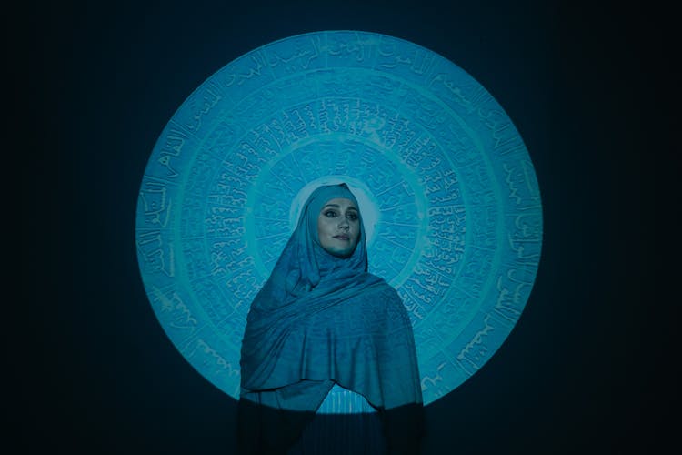 Woman In Blue Hijab Standing Beside Blue And White Wall